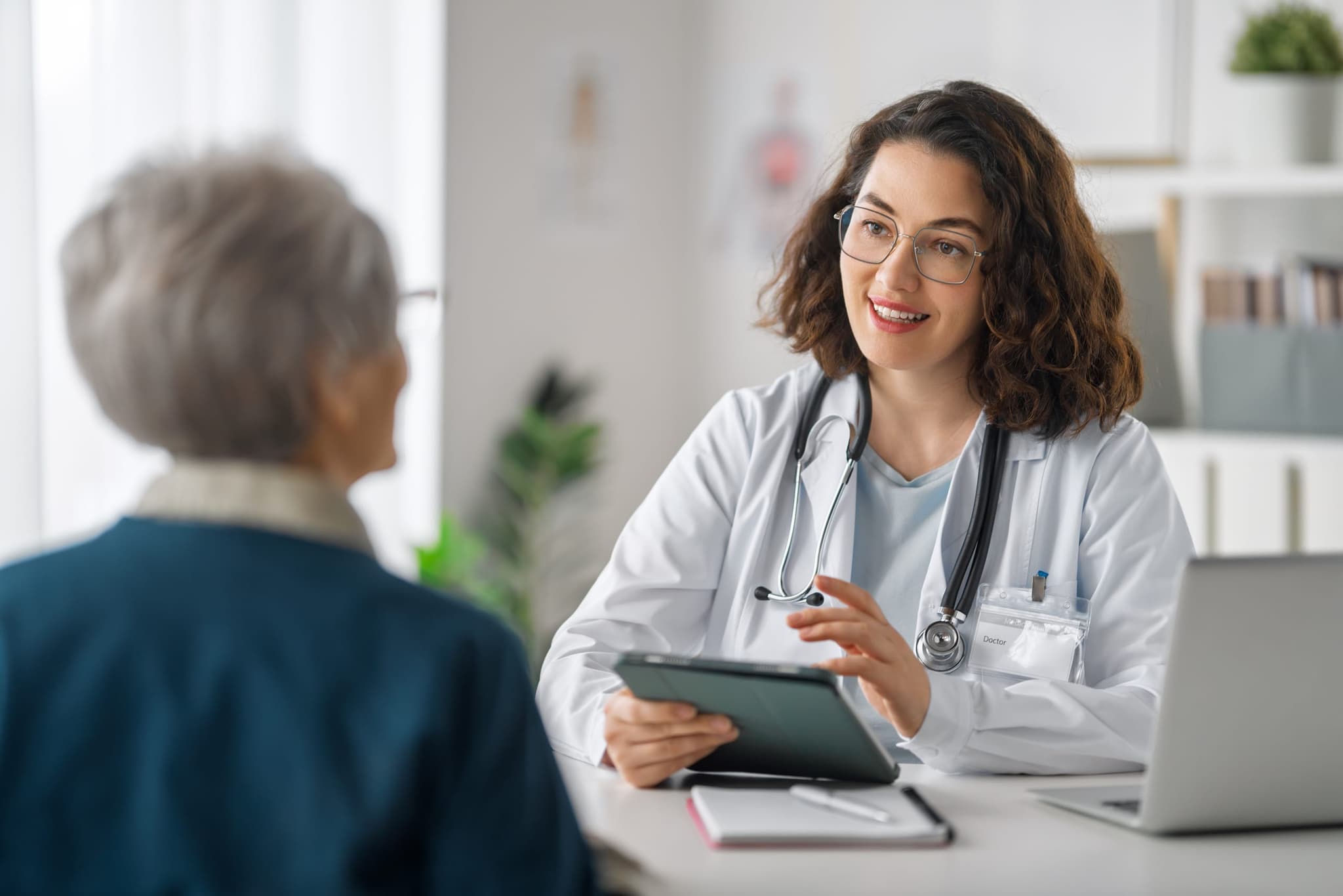 Una médica revisando resultados de laboratorio renal con un paciente en una tableta