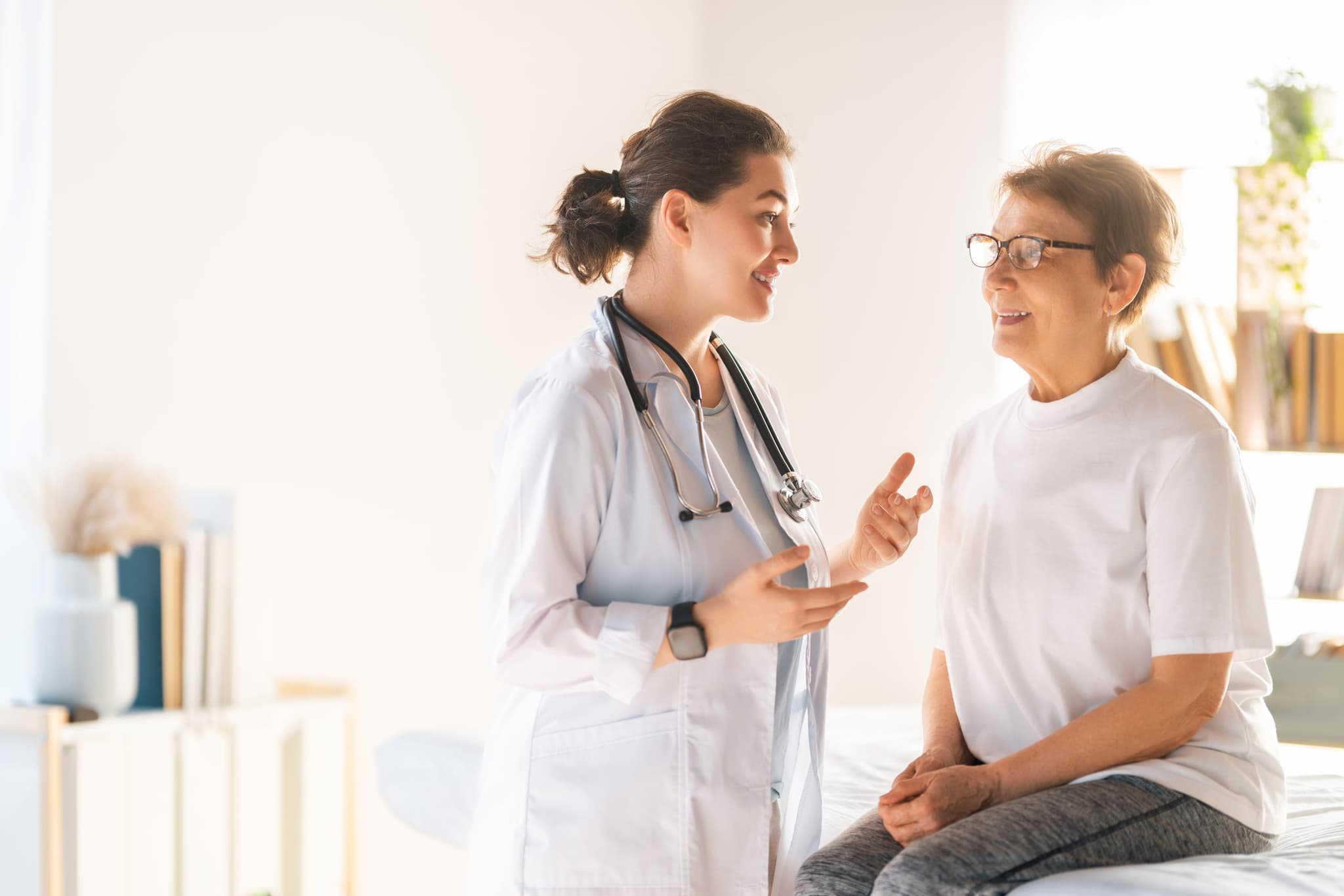 Una enfermera de infusión ajustando una vía intravenosa y conversando con una paciente sonriente